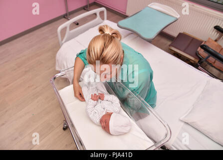 Una madre guarda al suo neonato in ospedale Foto Stock