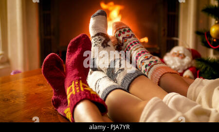 Primo piano immagine di genitori e bambini in piedi in caldo calze di lana che giace accanto al caminetto Foto Stock