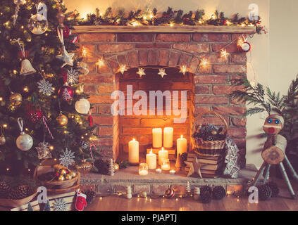 Impostazione di Natale sfondo, albero di Natale decorato, pigne nel cestello con caminetto sullo sfondo; candele un baubles Foto Stock