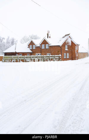 Una casa colonica in stile vittoriano in inverno con neve strada coperta in primo piano. Inghilterra, Regno Unito Foto Stock