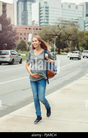 Felice gravidanza sana. Ritratto di gravidanza caucasica bionda e giovane donna caucasica camminando nella trafficata città urbana all'esterno. Bella slim si aspettano sportivo Foto Stock