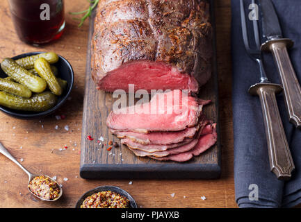 Arrosto di manzo sul tagliere. Sfondo di legno. Foto Stock