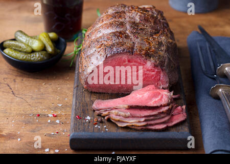 Arrosto di manzo sul tagliere. Sfondo di legno. Foto Stock