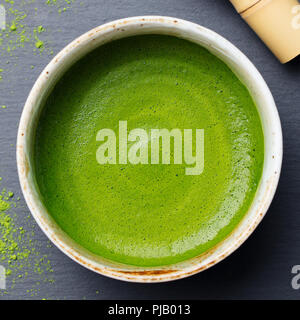 Matcha, il tè verde latte in una tazza. Grigio pietra dello sfondo. Vista dall'alto. Foto Stock