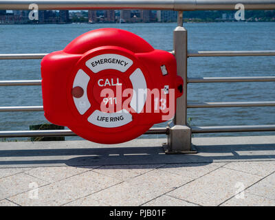 Di emergenza rosso anello di vita appesa sulla ringhiera accanto al fiume Foto Stock