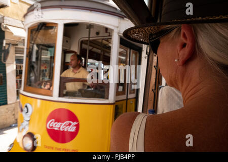 La donna vestita di bianco con cappello di paglia su un tram a Lisbona Foto Stock