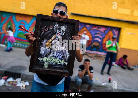 Un messicano adoratore di Santa Muerte (Santa morte) conserva una "Bandida" (una femmina bandit) opera d'arte durante un religioso pellegrinaggio a Città del Messico. Foto Stock