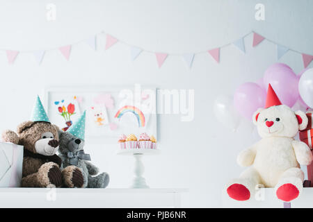 Orsetti in rocche sul tavolo con tortine su supporto in decorate per camera di compleanno Foto Stock