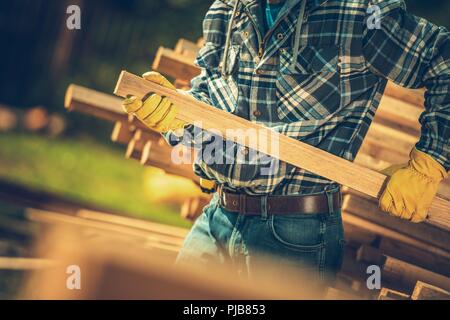 Acquisto di legno nella costruzione di Forniture Store. Contraente tirando trave di legno dalla pila. La scelta di diritto materiale da costruzione. Foto Stock