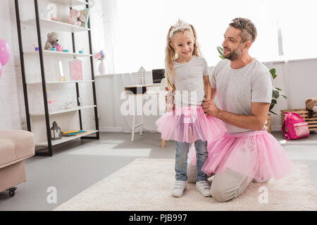 Padre e figlia in rosa tutu gonne sorridente a casa Foto Stock