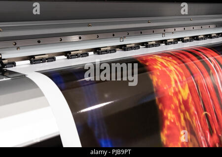 Grande stampante professionale, elaborazione grandi rotoli di vinile per campionamento del colore in un enorme ambiente di produzione. Foto Stock