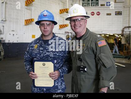 NORFOLK, Virginia (Luglio 9, 2018) - Master-at-Arms 2a classe Eric P. Atkinson, da Akron, Ohio, assegnato alla USS Gerald Ford (CVN 78) servizio di sicurezza, riceve il suo certificato di nomina al rango di sottufficiali seconda classe da Capt. Richard McCormack, Ford comandante. Atkinson è stato promosso dopo la sua selezione per il meritorio Programma di avanzamento. Foto Stock