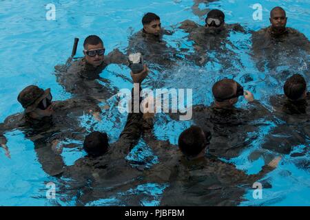 Marines attaccati alle operazioni Expeditionary Gruppo di addestramento, III Marine forza expeditionary gruppo informazioni di battistrada, acqua con mattoni di gomma durante un evento per scout nuotatori corso Luglio 12, 2018 al Camp Hansen Aquatics Centre, Okinawa, in Giappone. La scout nuotatori corso fornisce la Marine Corps con capacità anfibie mentre l'insegnamento Marines di diventare abili a lunga distanza di nuoto. Foto Stock