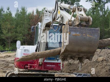 Stati Uniti Air Force Staff Sgt. Jeremy Burgos, membro dell'166Ingegnere Civile Squadron, Delaware Air National Guard, opera un retroescavatore per rimuovere eccesso di legno per bruciare, come parte di una fase di costruzione di Camp Kamassa in Crystal molle, Mississippi, luglio 11, 2018. Camp Kamassa saranno stati prima completamente accessibile ai portatori di handicap, anno camp agevolazione per gli adulti e per i bambini con bisogni speciali, che viene costruito su 326 acri capeggiate dal Dipartimento della Difesa prontezza innovativo programma di formazione. Foto Stock