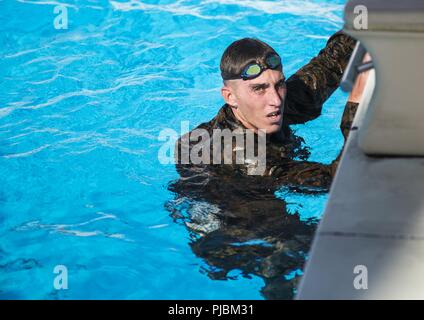 Sgt. Thomas Sargent, da Little Rock, Virginia, finiture a 500 metri di nuotare durante uno scout nuotatori corso Luglio 9, 2018 al Camp Hansen Aquatics Centre. La scout nuotatori corso fornisce la Marine Corps con capacità anfibie mentre l'insegnamento Marines di diventare abili a lunga distanza di nuoto. Sargent è attaccato a operazioni Expeditionary Gruppo di addestramento, III Marine forza expeditionary Informazioni Gruppo. Foto Stock