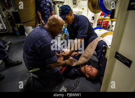 Oceano Pacifico (10 luglio 2018) - Capo di Boatswain Mate Louis Montealegre, a sinistra e di Boatswain Mate 3° di classe Edgar Chajon assistere Boatswain compagno del 3° di classe Dalton scintille durante la formazione medica a bordo guidato-missile destroyer USS Dewey (DDG 105). Dewey è in corso che partecipano a bordo del Pacifico (RIMPAC) Esercizio 2018. Venticinque nazioni, 46 navi, cinque sommergibili, circa 200 aerei, e 25.000 personale partecipano RIMPAC dal 27 giugno al 2 agosto in e intorno alle Isole Hawaii e la California del Sud. Il più grande del mondo marittimo internazionale esercitazione RIMPAC fornisce Foto Stock