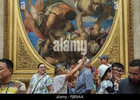 I visitatori di fronte al dipinto 'Jupiter Hockey irlandese Thunderbolts a vizi' dal Rinascimento italiano pittore veronese (1556) visualizzato nel museo del Louvre a Parigi, Francia. Foto Stock