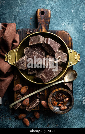 Cioccolato fondente pezzi frantumato e fave di cacao. Sfondo di cioccolato Foto Stock