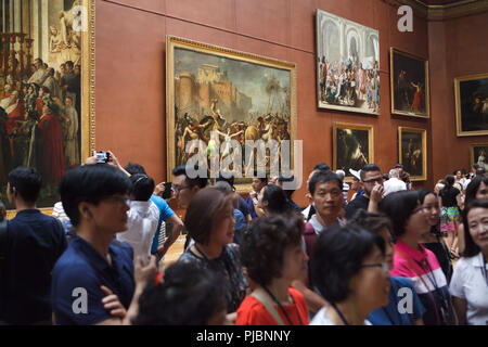 Folla di visitatori davanti al dipinto 'L'intervento di Sabine' dal francese pittore neoclassico Jacques-Louis David (1799) visualizzato nel museo del Louvre a Parigi, Francia. Foto Stock