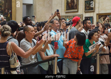 I visitatori utilizzano il loro smartphone per scattare foto e selfies con il famoso dipinto 'Mona Lisa' ('La Gioconda") dagli italiani pittore rinascimentale Leonardo da Vinci visualizzato nel museo del Louvre a Parigi, Francia. Foto Stock
