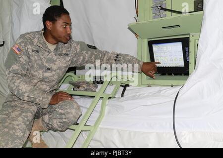 Sgt. Hassan Scott di U.S. Esercito della riserva 628th in avanti il team chirurgico fuori di Fort Sam Houston, Texas, spiega le funzioni di una sostanza chimica biologica riparo protettivo M8E1 distribuito su un sito di formazione da durante il Global Medic esercizio luglio 13 a Fort Hunter Liggett, California. Il veicolo mobile montato su shelter è auto-dispiegabile e serve come un self-contained protettiva dell'aria condizionata sistema che è privo di contaminazione. Esso consente di sostegno militare al personale di lavorare in modo sicuro e facilmente senza dover indossare chimico-biologico abbigliamento protettivo. Foto Stock