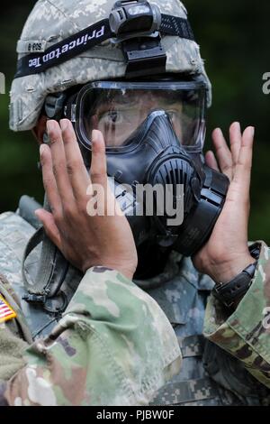 Stati Uniti Il personale dell'esercito Sgt. Duane Butler controlla il sigillo sulla sua maschera a gas durante l'esercito Materiel del comando guerriero migliore concorrenza 9-11 luglio 2018, presso il Camp Atterbury, Indiana. Durante i tre giorni di gara, i soldati sono stati testati su base e avanzate attività di guerriero e trapani, si trovano di fronte a sfide prova la loro forza fisica e mentale. Foto Stock