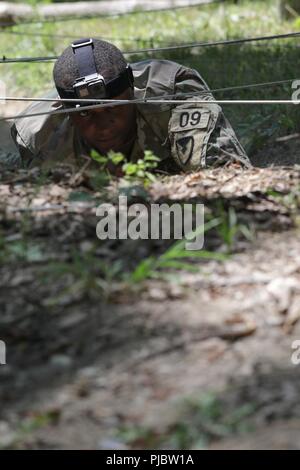 Stati Uniti Il personale dell'esercito Sgt. Duane Butler esegue la bassa crawl evento presso il corso di fiducia durante l'esercito Materiel del comando guerriero migliore concorrenza 9-11 luglio 2018, presso il Camp Atterbury, Indiana. Durante i tre giorni di gara, i soldati sono stati testati su base e avanzate attività di guerriero e trapani, si trovano di fronte a sfide prova la loro forza fisica e mentale. Foto Stock