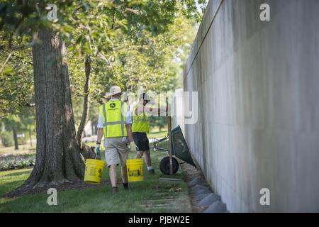 Volontari raddrizzare, livello e sostituire le pietre rotte al di fuori della Corte Columbarium 1 presso il Cimitero Nazionale di Arlington Arlington, Virginia, 16 luglio 2018. Oltre 400 volontari professionisti del paesaggio ha partecipato in Associazione Nazionale dei professionisti del paesaggio' xxii rinnovo annuale e ricordo evento presso il Cimitero Nazionale di Arlington. Volontari aerato turf, piantato fiori, di cui i tubi di irrigazione e illuminazione installata una protezione su diversi alberi. Foto Stock