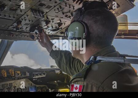 Oceano Pacifico (15 luglio 2018) Royal Canadian Air Force Caporale David Bettle, un tecnico di volo con un canadese Aurora (CP 140) aeromobile, regola i controlli nella cabina di pilotaggio durante il volo come parte di una sub-caccia scenario durante il cerchio del Pacifico (RIMPAC) esercizio. Venticinque nazioni, 46 navi, cinque sommergibili, circa 200 aerei e 25.000 personale partecipano RIMPAC dal 27 giugno al 2 agosto in e intorno alle Isole Hawaii e la California del Sud. Il più grande del mondo marittimo internazionale esercitazione RIMPAC offre una singolare opportunità di formazione promuovendo e sostenendo la coop Foto Stock