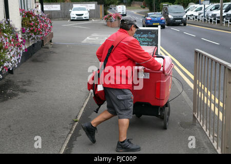 Villaggio portalettere usando il suo tondo postale consegna trolley in Bawtry, Foto Stock