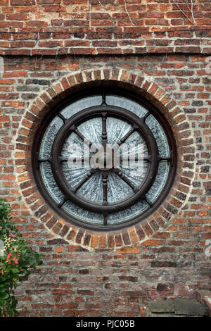 Un giro della ruota esterna finestra integrata in una casa rossa parete di mattoni Foto Stock