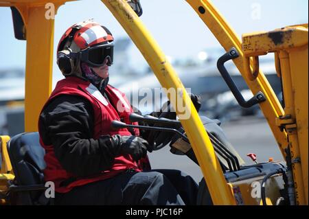 Oceano atlantico (17 luglio 2018) di aviazione di Boatswain Mate (manipolazione) 2a classe Jennifer Canterbury opera un carrello sul ponte di volo a bordo della Nimitz-class portaerei USS Harry Truman (CVN 75). Harry Truman è attualmente implementata come parte di una costante rotazione delle forze degli Stati Uniti sostenere le operazioni di sicurezza marittima nelle acque internazionali in tutto il mondo. Foto Stock