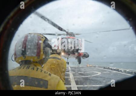 Un membro dell'equipaggio a bordo del guardacoste Stratton (WMSL 752) dirige lo sbarco di am MH-60 elicottero Jayhawk equipaggio vicino lo stretto di Bering, 10 luglio 2018. Il Stratton equipaggio è il pattugliamento al di sopra del Circolo Polare Artico a sostegno del funzionamento dello schermo Artico 2018. Coast Guard Foto Stock