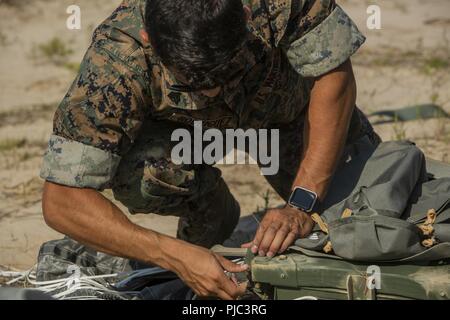 Un U.S. Marine con il secondo battaglione di ricognizione, seconda divisione Marine, rimuove un paracadute da un pacchetto di rialimentazione durante un rifornimento di esercizio di recupero di Camp Lejeune, N.C., 11 luglio, 2018. La formazione ha migliorato il Marines' abilità per tatticamente recuperare le forniture e le attrezzature in preparazione per il potenziale del mondo reale in missioni di ambienti austeri. Foto Stock