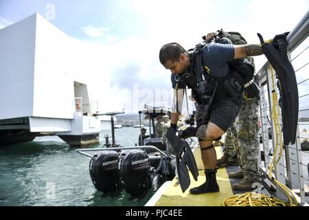 PEARL HARBOR (13 luglio 2018) La comunicazione di massa Specialist 1a classe Arthurgwain L. Marquez, assegnato al combattimento della flotta del Pacifico della fotocamera, mette sulle sue alette in preparazione per un tuffo presso la USS Arizona Memorial durante il cerchio del Pacifico (RIMPAC) Esercizio, luglio 13. Venticinque nazioni, 45 navi, cinque sommergibili, circa 200 aerei, e 25.000 personale partecipano RIMPAC dal 27 giugno al 2 agosto in e intorno alle Isole Hawaii e la California del Sud. Il più grande del mondo marittimo internazionale esercitazione RIMPAC offre una singolare opportunità di formazione promuovendo e sostenendo la cooperativa Foto Stock