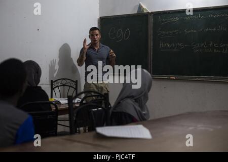 Un U.S. Soldato dell'esercito assegnato all'affari civili battaglione, spiega la lezione per gli studenti del Gibuti durante la classe inglese in Tadjourah, Gibuti, 10 luglio 2018. Il Affari Civili Lead del team inglese di gruppi di discussione in tutta la combinazione di area per operazioni congiunte, a rafforzare i legami locali nella regione fornendo al contempo opportunità per i bambini di ampliare le loro conoscenze e competenze con la lingua inglese. Foto Stock