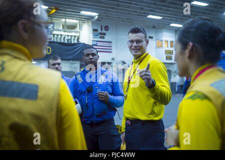Oceano Pacifico (12 luglio 2018) di aviazione di Boatswain Mate (manipolazione) 1a classe Mathew Bennett, da Atlanta, conduce un riepilogo finale a seguito del trasporto di aerei negli hangar bay dell'assalto anfibio nave USS Bonhomme Richard (LHD 6). Bonhomme Richard è attualmente in corso negli Stati Uniti La terza area della flotta di operazioni. Foto Stock