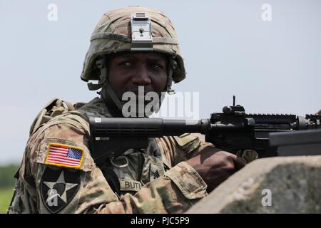 Stati Uniti Il personale dell'esercito Sgt. Duane Butler attende il segnale di fuoco la M4A1 carbine in corrispondenza di un intervallo durante l'esercito Materiel del comando guerriero migliore concorrenza 9-11 luglio 2018, presso il Camp Atterbury, Indiana. Durante i tre giorni di gara, i soldati sono stati testati su base e avanzate attività di guerriero e trapani, si trovano di fronte a sfide prova la loro forza fisica e mentale. Foto Stock