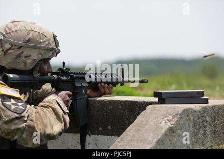 Stati Uniti Il personale dell'esercito Sgt. Duane Butler incendi di M4A1 carbine giù gamma durante l'esercito Materiel del comando guerriero migliore concorrenza 9-11 luglio 2018, presso il Camp Atterbury, Indiana. Durante i tre giorni di gara, i soldati sono stati testati su base e avanzate attività di guerriero e trapani, si trovano di fronte a sfide prova la loro forza fisica e mentale. Foto Stock