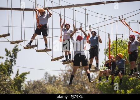 I candidati in Sunburst sfida della gioventù dell Accademia Classe 22 Firehawks plotone lavorare il loro modo attraverso un intricato sistema di corda ostacoli mentre l'ascendente di una zip line finish, luglio 19, 2018 all'Orange County ropes course di Anaheim, in California. Le funi corso offre ai candidati la possibilità di spingere se stessi sia mentalmente e fisicamente, per costruire la fiducia e di iniziare a lavorare come un team mentre è ancora in fase di acclimatazione della sfida del programma. Foto Stock