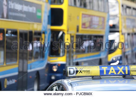 Un segno di taxi sul tetto di un taxi di Dublino con autobus di Dublino in background Foto Stock