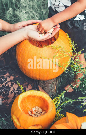 Una chiusura di una donna e bambino mani tira le sementi e materiale fibroso da una zucca prima della scultura per Halloween. jack-o-lantern. Tonica foto. daugh Foto Stock