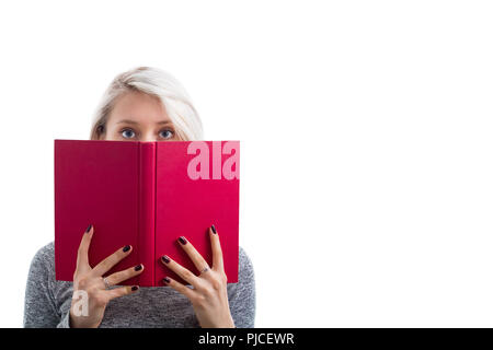 Ritratto di una ragazza giovane e carina di nascondersi dietro un open standard Red Book e guardando la paura alla telecamera isolate su sfondo bianco. Foto Stock