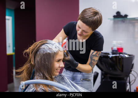 Parrucchiere professionale colorazione dei capelli della donna client presso studio Foto Stock