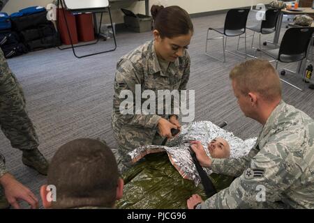 Il personale dal 673d Medical Group finire di avvolgere il corpo di un "ferito" Airman con un foglio di copertura durante un combattimento tattico Casualty Care corsi a base comune Elmendorf-Richardson, Alaska, 12 luglio, 2018. Questa procedura è considerata altamente efficace a prevenire l'ipotermia su un trauma del paziente. Foto Stock