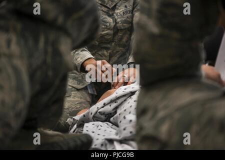 Stati Uniti Air Force Master Sgt. Demetris Johnson, un multi-unità di servizio di volo capo assegnato al 673d Inpatient Operations Squadron, incarica 673d gruppo medico personale per eseguire una decompressione ad ago per una tensione pneumotorace durante un combattimento tattico Casualty Care corsi a base comune Elmendorf-Richardson, Alaska, 12 luglio, 2018. Questa procedura è necessaria quando aria entra nella cavità toracica impedendo il polmone di espansione. L'ago rilascia aria, lasciando il polmone espandono e il paziente respira ancora. Foto Stock