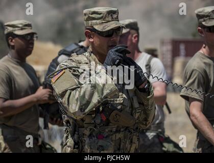 Primo Lt. Rosado Alexander, U.S. La riserva di esercito di delegato per la 348Polizia Militare Company, invita la radio mentre i soldati escort un 'nemico del prigioniero di guerra' roleplayer attraverso la loro detenzione Teatro Facility a combattere la formazione per il supporto di esercizio (CSTX) a Fort Hunter Liggett, California, 21 luglio 2018. Durante l'esercizio scenario, la polizia militare sono responsabili per un teatro fermo impianto per processi e proteggere fino a 4.000 nemico di prigionieri di guerra e anche di gestire una detenzione area di contenimento ad accogliere sfollati civili. La polizia militare dispone di una vasta gamma di responsabilità Foto Stock