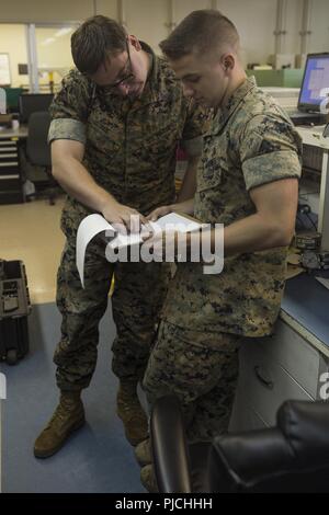 Sgt. Justin W. Ivie, sinistra e Cpl. Davis E. Steiner, a destra di guardare al di sopra di un foglio di calcolo per un veicolo automated diagnostic system Luglio 23, 2018 a Camp Kinser, Okinawa, in Giappone. Il foglio di calcolo viene utilizzato per assicurarsi che le calibrazioni e il software di diagnostica sono corrette per il veicolo automated diagnostic system. Ivie e Steiner sono misure di test e per apparecchiature di diagnostica con i tecnici di manutenzione elettronica azienda logistica di combattimento reggimento 35, terzo Marine Logistics Group. Ivie è un nativo di Oviedo, Florida. Steiner è un nativo di Atlanta, Georgia. Foto Stock
