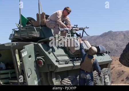 Stati Uniti Marine Corps Staff Sgt. Daniel Ragan, top, il gruppo leader, luce ricognizione corazzato Training Company (LART), avanzati di formazione di fanteria battaglione, (AITB) prende un M240B mitragliatrice da PFC. Cameron mulini, uno studente con lart Co., AITB, al Marine Corps base Camp Pendleton, California, 24 luglio 2018. Ragan montato un M240B mitragliatrice sulla luce di un veicolo blindato per utilizzare durante un esercizio di formazione. Foto Stock