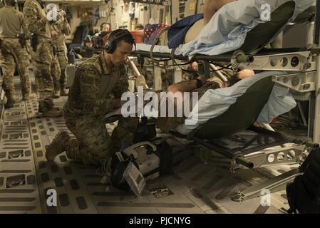 Senior Airman Eric Mukes, volo medic, 455th Expeditionary evacuazione di medicina aeronautica Squadron (EAES), Bagram Airfield, Afghanistan, i record di un paziente di segni vitali durante un controllo periodico in rotta di Ramstein Air Base, Germania, 21 luglio 2018. Il avieri del 455th EAES sono tasked con il trasporto di feriti negli Stati Uniti e la NATO partner membri del servizio di assistenza a lungo termine di impianti di trattamento. Foto Stock